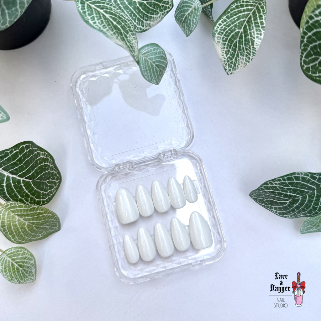 Set of Almond handmade custom white press-on nails in a clear case with green leaves on a white background