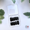 Set of Square handmade custom black press-on nails in a clear plastic case on a white background with green leaf patterns.