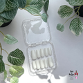 Set of Square handmade custom white press-on nails in a clear plastic case with green leafy plants in the background