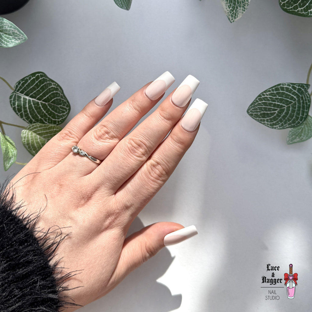 Hand with square handmade custom light pink deep french press on nails  on a light grey background with leaf patterns